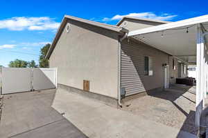 View of home's exterior featuring a carport, a gate, fence, and stucco siding