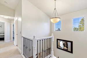 Hallway with baseboards, carpet flooring, and an upstairs landing