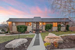 Mid-century inspired home with a standing seam roof, brick siding, metal roof, and a lawn