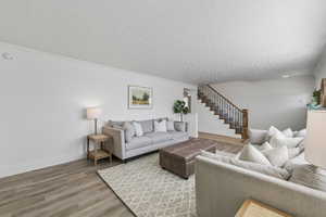 Living room featuring baseboards, ornamental molding, wood finished floors, stairs, and a textured ceiling