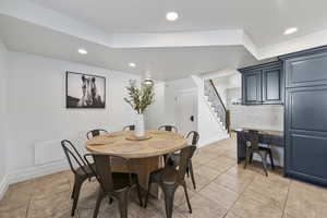 Dining area with light tile patterned floors, stairway, and recessed lighting