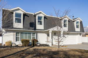 View of front of home featuring brick siding, a shingled roof, concrete driveway, fence, and a garage
