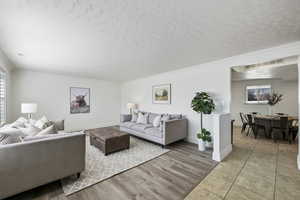 Living area with baseboards, visible vents, ornamental molding, wood finished floors, and a textured ceiling