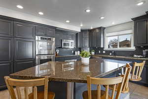 Kitchen with decorative backsplash, a breakfast bar area, stainless steel appliances, and a sink