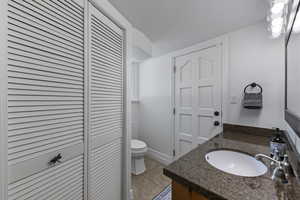 Bathroom featuring a closet, vanity, toilet, and tile patterned floors