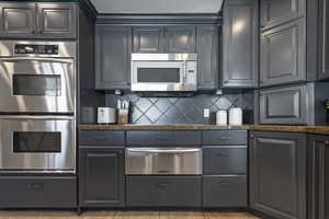 Kitchen featuring backsplash, stainless steel appliances, a warming drawer, and light tile patterned flooring