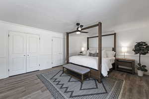 Bedroom featuring ceiling fan, wood finished floors, crown molding, a textured ceiling, and multiple closets