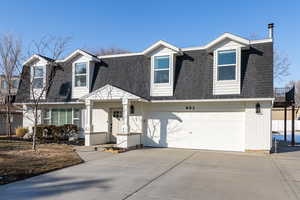 Dutch colonial with roof with shingles, brick siding, and driveway