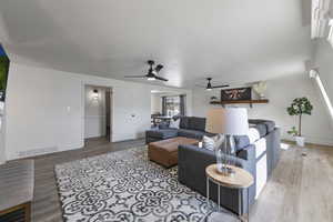 Living room with visible vents, ceiling fan, baseboards, and wood finished floors