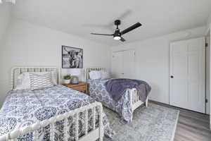 Bedroom with baseboards, a ceiling fan, brick wall, wood finished floors, and a closet