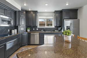 Kitchen featuring a sink, stainless steel appliances, a warming drawer, backsplash, and light tile patterned flooring
