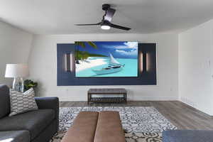 Cinema room with baseboards, ceiling fan, visible vents, and wood finished floors