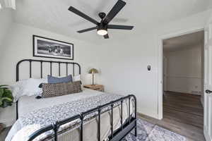 Bedroom featuring ceiling fan, visible vents, baseboards, and wood finished floors