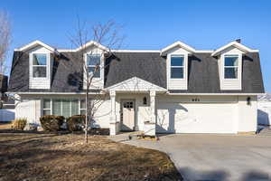 View of front facade featuring a shingled roof, concrete driveway, brick siding, and a garage