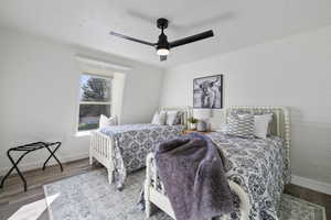 Bedroom with brick wall, wood finished floors, a ceiling fan, and baseboards