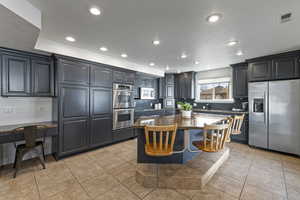 Kitchen with light tile patterned flooring, a kitchen island, visible vents, appliances with stainless steel finishes, and tasteful backsplash