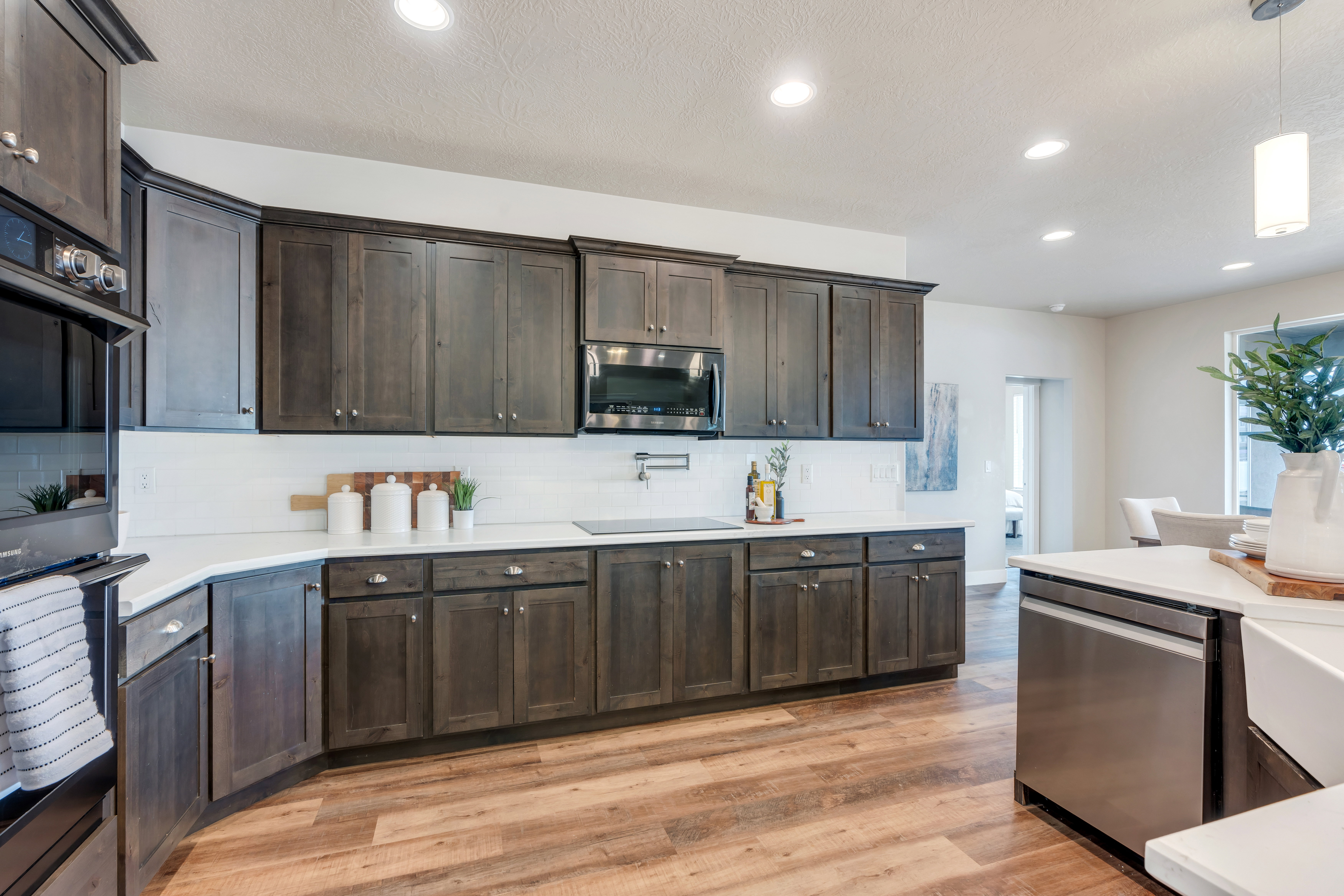 Kitchen with dark brown cabinetry, appliances with stainless steel finishes, light wood finished floors, and backsplash