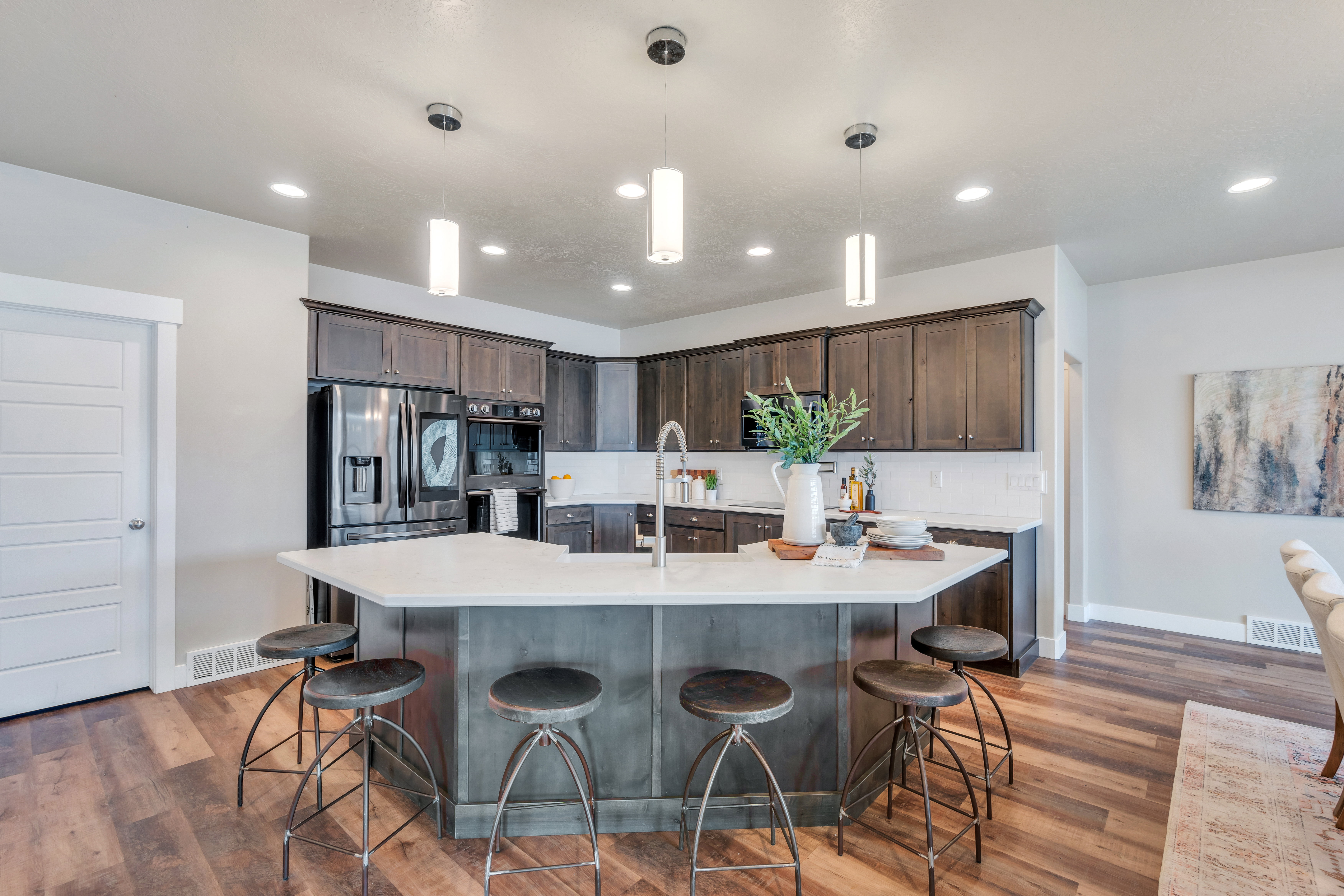 Kitchen featuring wood finished floors, visible vents, dark brown cabinets, appliances with stainless steel finishes, and light countertops