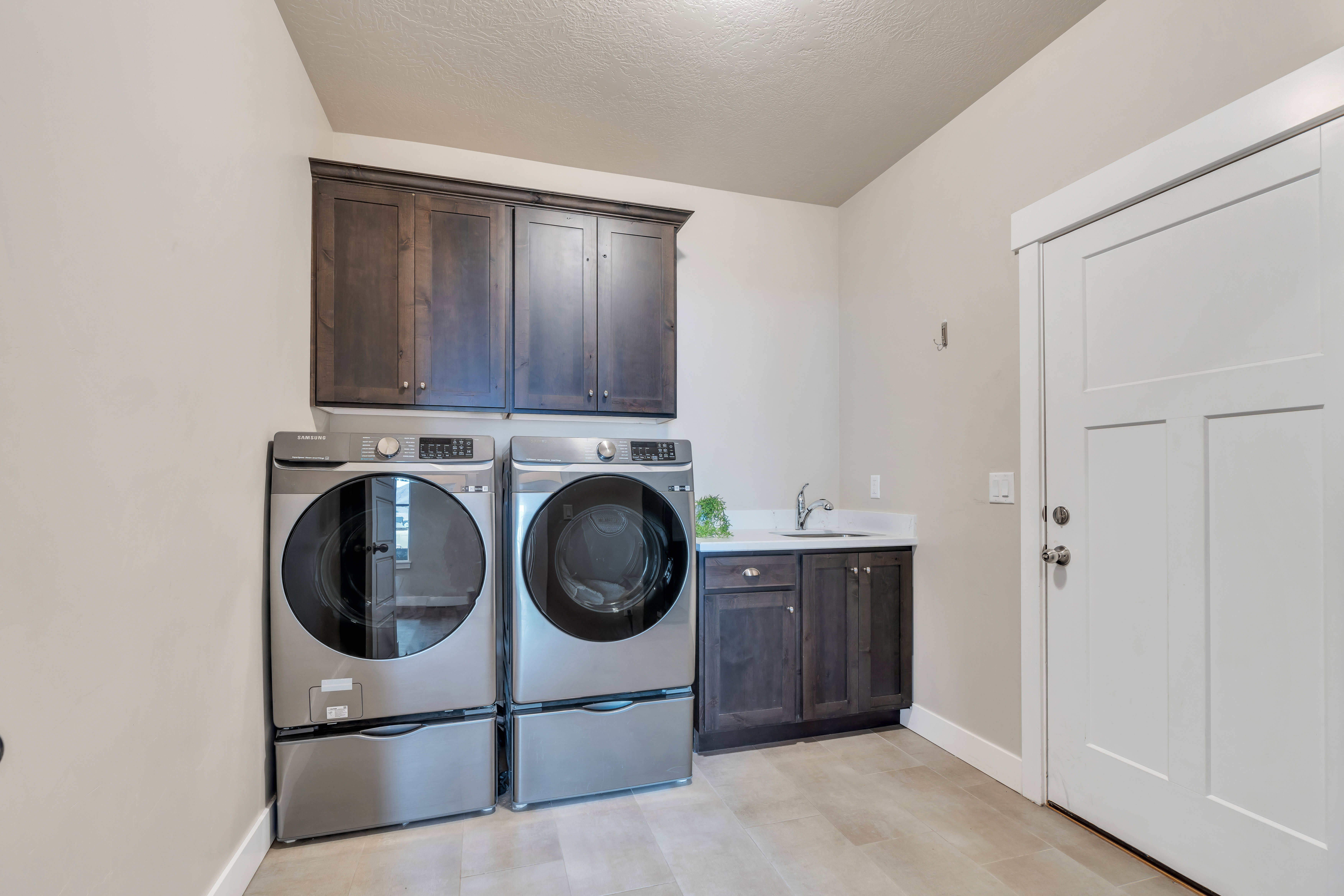 Clothes washing area featuring cabinet space, baseboards, washing machine and clothes dryer, a textured ceiling, and a sink