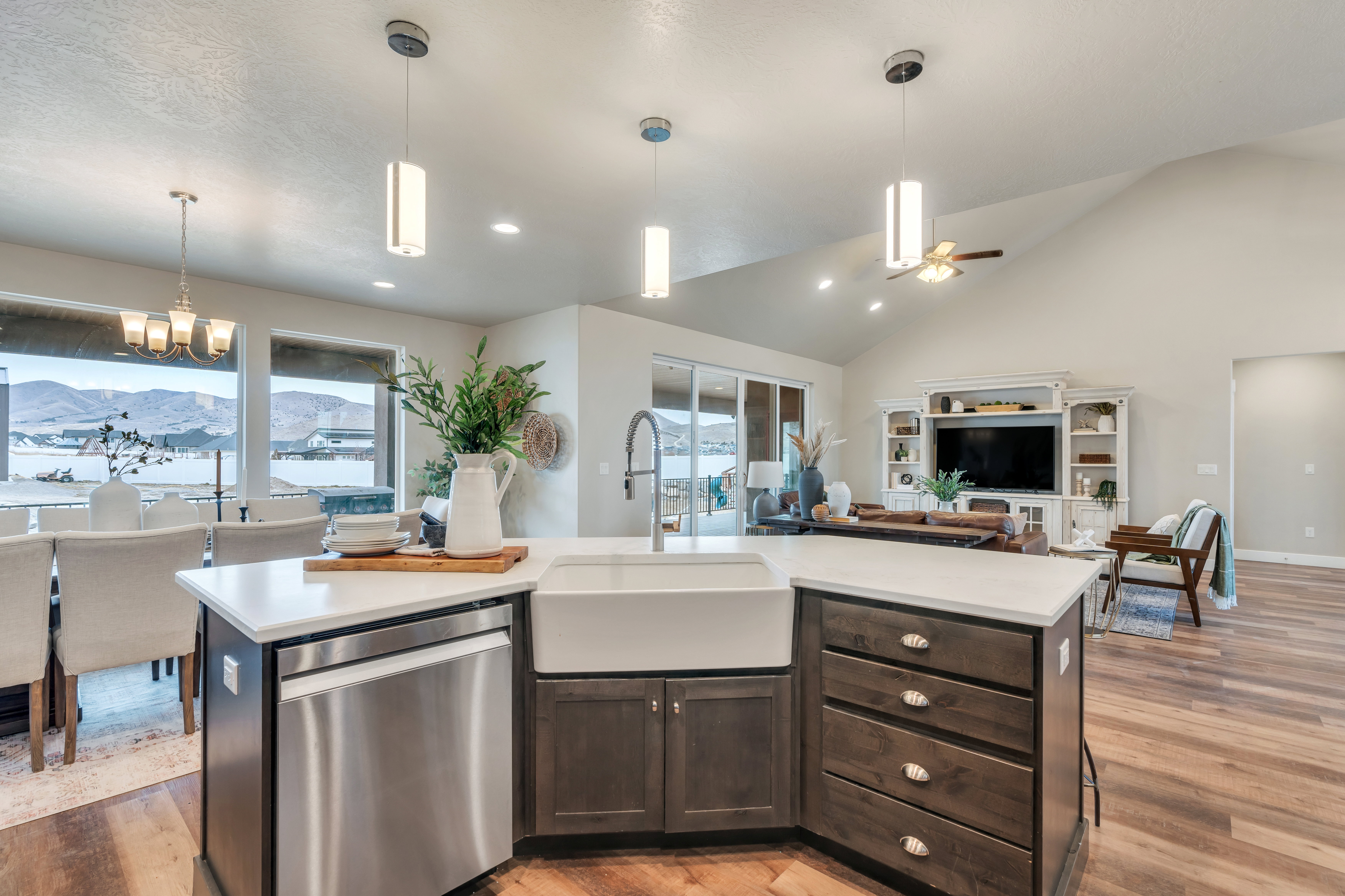 Kitchen featuring light countertops, stainless steel dishwasher, open floor plan, dark brown cabinetry, and a sink