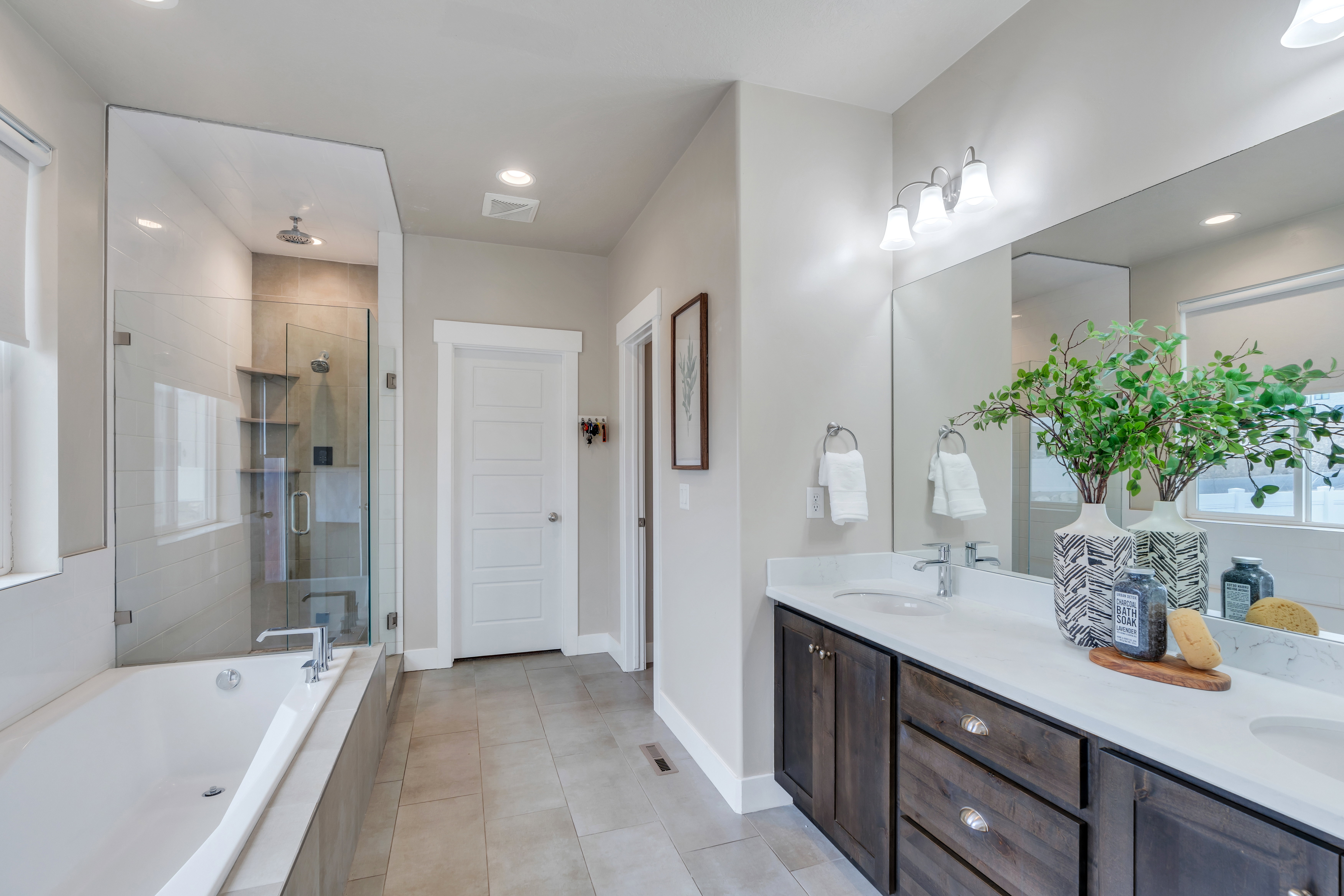 Full bath featuring double vanity, a stall shower, a garden tub, and a sink