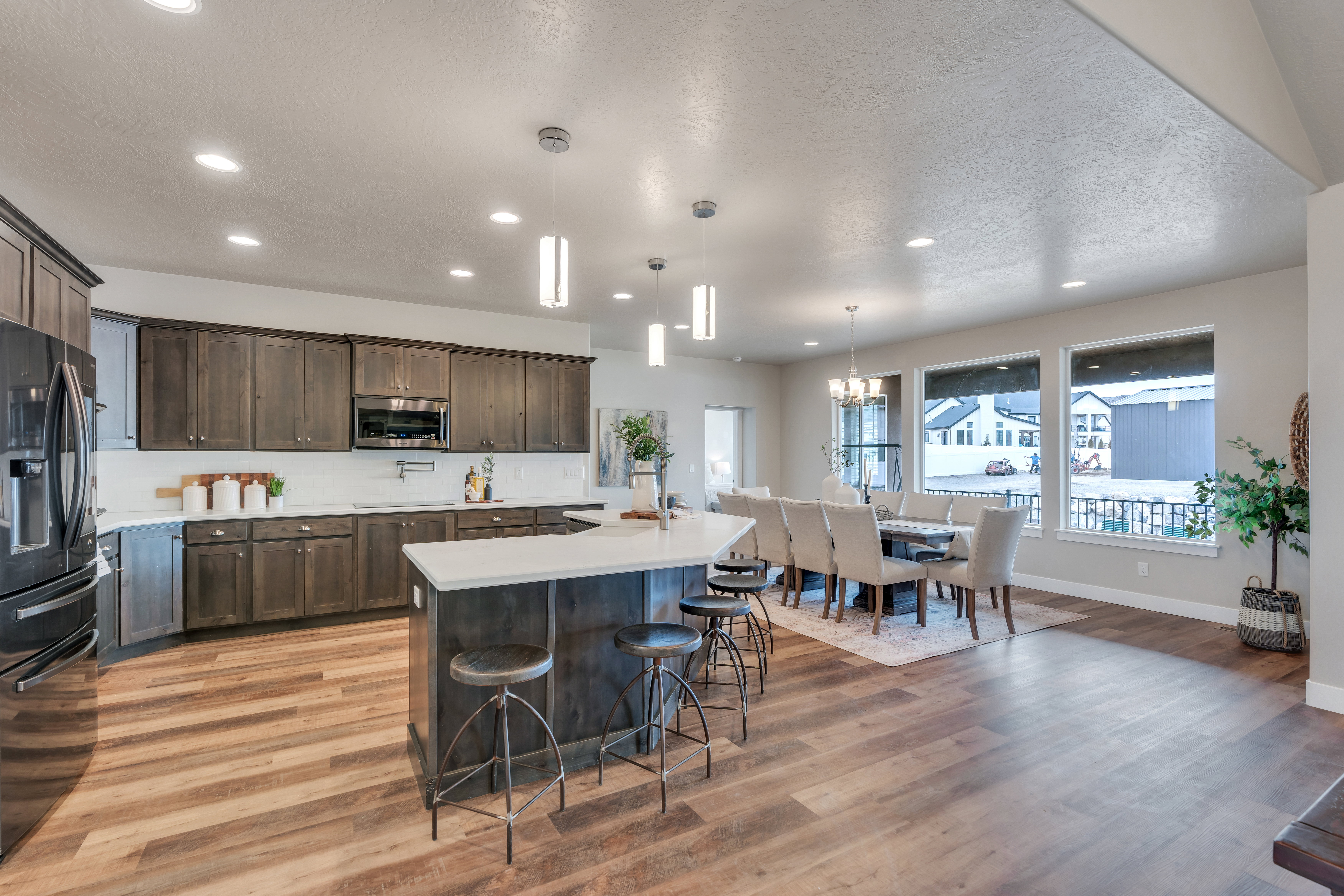 Kitchen featuring dark brown cabinetry, stainless steel microwave, a kitchen breakfast bar, black refrigerator with ice dispenser, and light countertops
