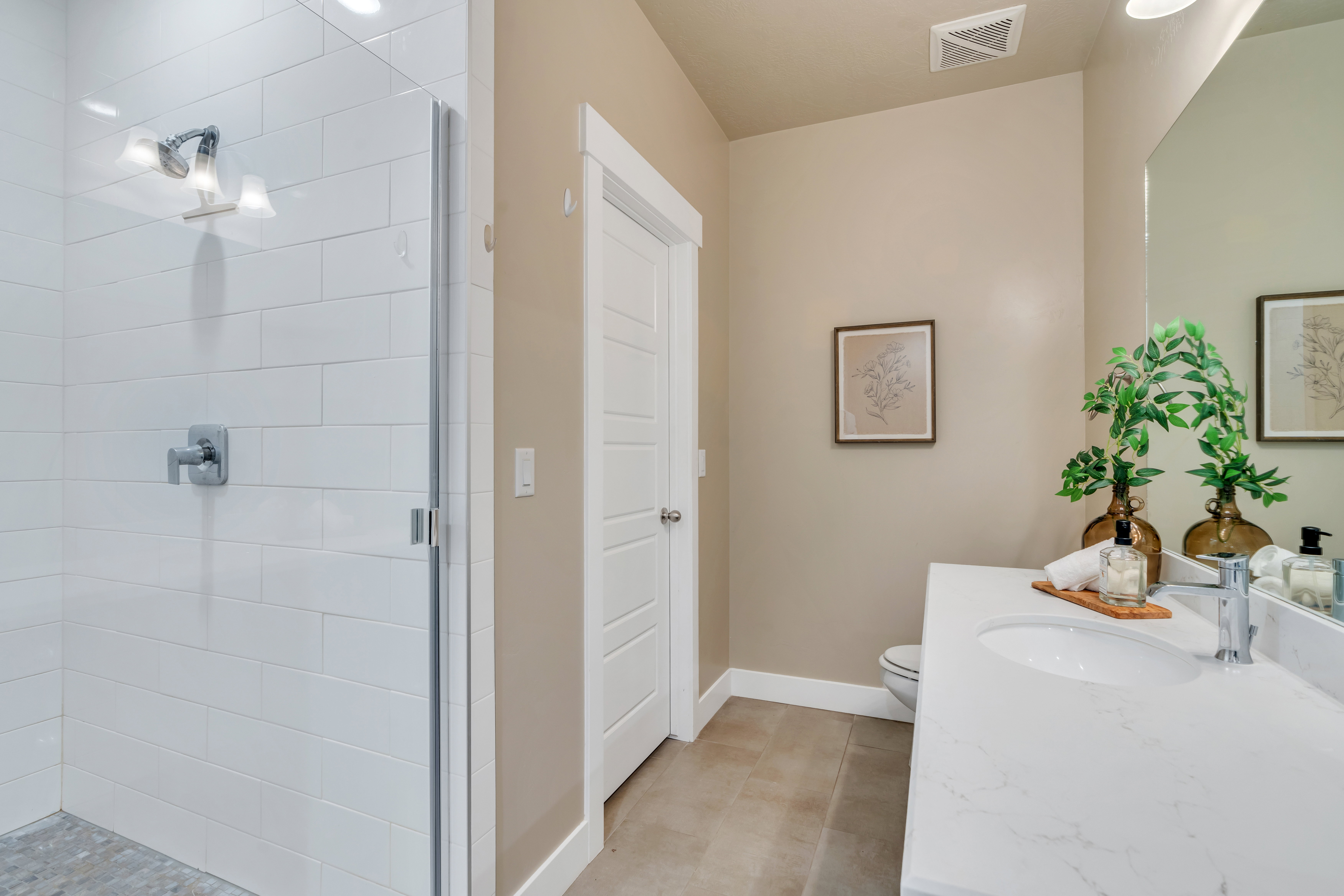 Full bath with toilet, vanity, visible vents, baseboards, and a shower stall