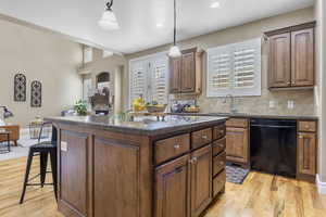 Kitchen featuring a center island, black dishwasher, a sink, and decorative backsplash