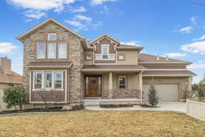 View of front of property featuring a garage, concrete driveway, front yard