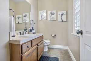 Powder Bath featuring toilet, stone finish flooring, vanity