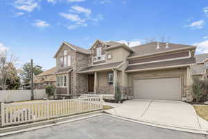 View of front of property featuring driveway, a fenced front yard, a garage