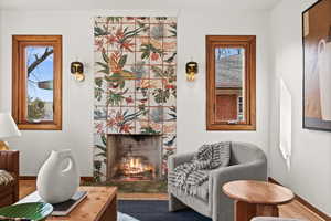 Living area with a tiled fireplace, baseboards, and wood finished floors