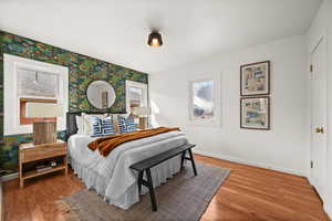 Bedroom featuring wallpapered walls, baseboards, and wood finished floors