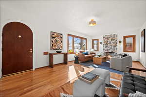 Living area featuring light wood finished floors, baseboards, arched walkways, and a large fireplace