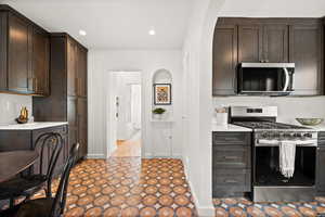 Kitchen featuring dark brown cabinetry, baseboards, stainless steel appliances, light countertops, and recessed lighting