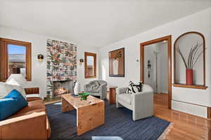 Living area featuring a large fireplace, wood finished floors, visible vents, and baseboards