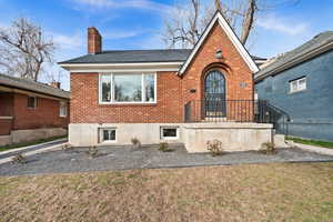 View of front of house featuring brick siding, a chimney, and a front lawn