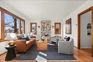 Living room with a warm lit fireplace, a textured ceiling, baseboards, and wood finished floors