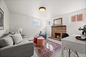 Carpeted living room with baseboards and a stone fireplace