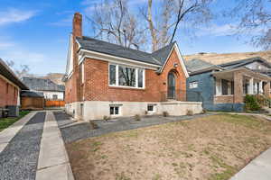 Bungalow-style home with central AC, brick siding, a chimney, and a front yard