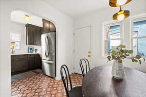 Kitchen with freestanding refrigerator, light countertops, arched walkways, and dark brown cabinets