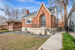 View of front of home with a chimney, a front lawn, and brick siding