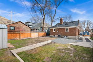 Back of property with cooling unit, brick siding, fence, and a chimney