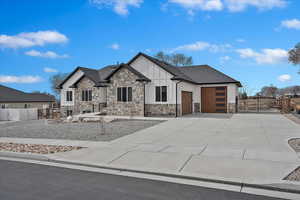 View of front of property featuring a garage, concrete driveway, board and batten siding, and a gate