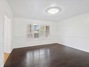 Empty room featuring baseboards, ornamental molding, and wood finished floors