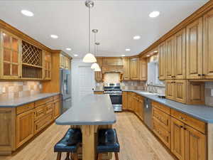 Kitchen featuring light wood-type flooring, a kitchen island, a breakfast bar area, and stainless steel appliances