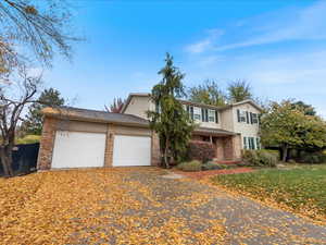 Traditional home featuring a garage, aphalt driveway, and brick siding