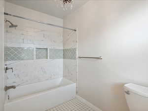 Bathroom featuring toilet, washtub / shower combination, baseboards, and tile patterned floors