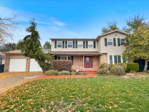 Traditional-style house featuring driveway, an attached garage, a front yard, and brick siding