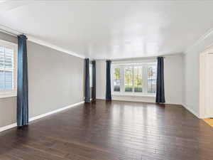 Spare room featuring ornamental molding, wood finished floors, and baseboards